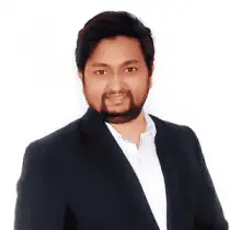 A middle aged man dressed in a navy blue suit with facial hair resembling a goatee